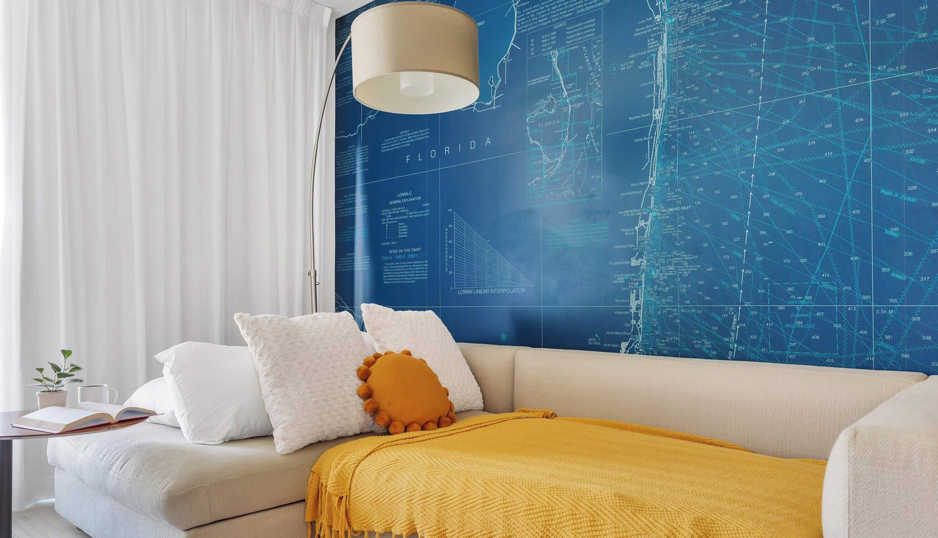 Ein modernes Wohnzimmer mit einer großen Wandkarte, einem Sofa und einer Lampe.