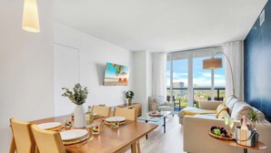 Ein modernes Wohnzimmer mit Essbereich, großen Fenstern und Blick auf die Stadt.