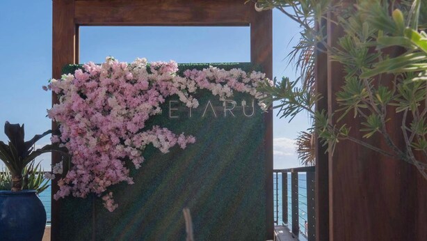 Eine Holzhütte mit einem Schild, auf dem 'ETARU' steht, verziert mit rosa Blüten.