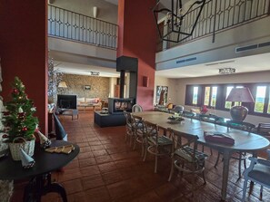 A spacious living area with a fireplace, a dining table, and a staircase leading to an upper level. - Las Pazuelas, the perfect rural getaway (Parrillas)