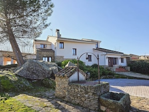 A two-story house with a stone foundation, a tiled roof, and a paved driveway.