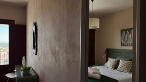 A hotel room with a bed, a desk, a chair, a potted plant, and a view of the city. - Las Pazuelas, the perfect rural getaway (Parrillas)