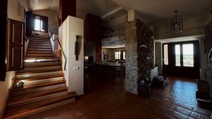 A spacious interior with a staircase leading to a second floor, a stone accent wall, and a large open dining area. - Las Pazuelas, the perfect rural getaway (Parrillas)