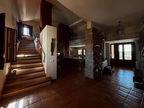 Ein geräumiger Innenraum mit einer Treppe, die zu einer zweiten Etage führt, einer Wand mit Steinverkleidung und einem großzügigen, offenen Essbereich.
