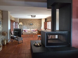 A living room with a stone wall, a sofa, a television, and a fireplace.
