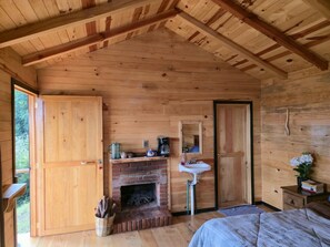 A wooden cabin interior with a fireplace, a bed, and a wooden door.