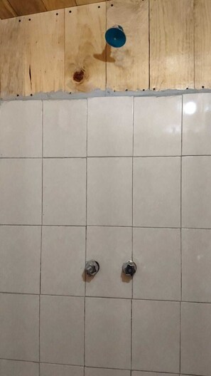 A tiled wall with two metal fixtures, possibly for water or gas.