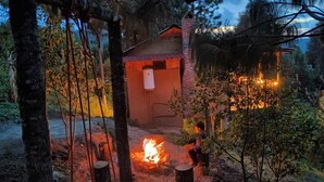 Eine rustikale Outdoor-Umgebung mit einer Holzkonstruktion, einer Feuerstelle und einer Schaukel.