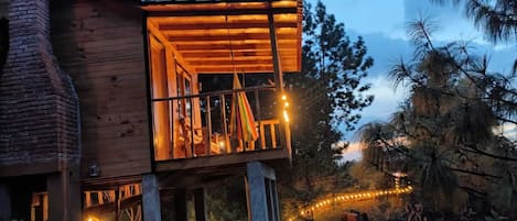 Una cabaña de madera con balcón, rodeada de árboles.