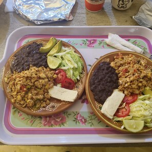 Two plates of food with beans, avocado, lettuce, and tomatoes on a tray.