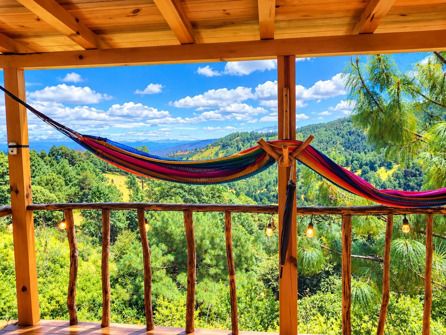 A hammock suspended between wooden beams with a view of a lush green landscape.