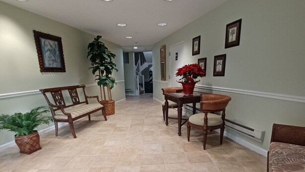 A hallway with a bench, chairs, a table, potted plants, and framed pictures on the walls. - Wonderful condo with cool AC, pool in charming Ship Bottom.Very spacious studio. (Ship Bottom)