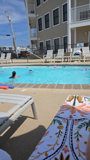 A swimming pool area with lounge chairs and a poolside table. - Wonderful condo with cool AC, pool in charming Ship Bottom.Very spacious studio. (Ship Bottom)