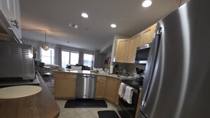 A modern kitchen with stainless steel appliances, wooden cabinets, and a central island. - Wonderful condo with cool AC, pool in charming Ship Bottom.Very spacious studio. (Ship Bottom)