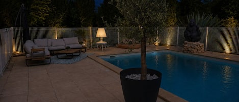 A poolside area with a seating arrangement and a lamp.
