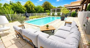 A poolside area with a seating arrangement, a pool, and a fenced garden. - Petite maisonnette avec accès piscine (Montauban)