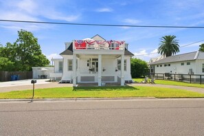 A two-story white house with a porch, a small attached garage, and a fenced yard. - The 1890 House where History meets the Horizon (Rockport)