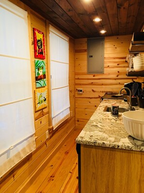 Un intérieur en bois avec un espace cuisine comprenant un comptoir en granit, un évier et un meuble de rangement au-dessus.