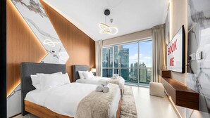 Moderni hotellihuone, jossa on suuri sänky, työpöytä ja näkymä kaupunkiin.