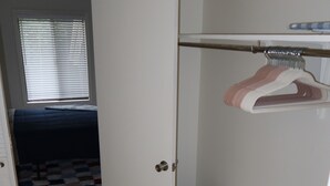 Quarto com cama, guarda-roupa e armário com espaço para pendurar.