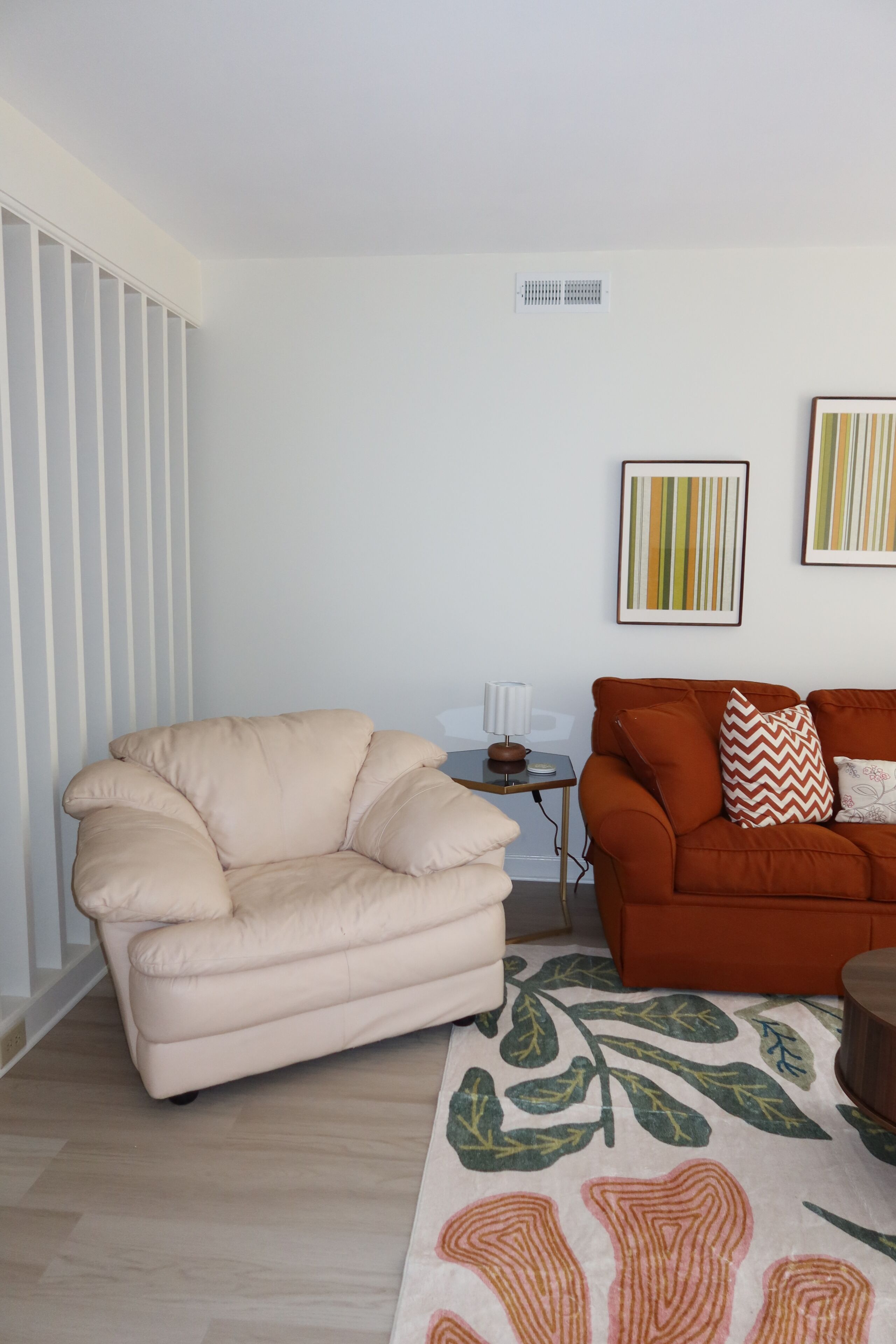 A living room with a beige armchair, an orange sofa, and a patterned rug.