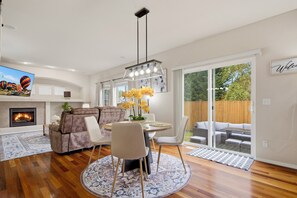 Una sala de estar moderna con chimenea, un comedor y vistas al patio trasero.