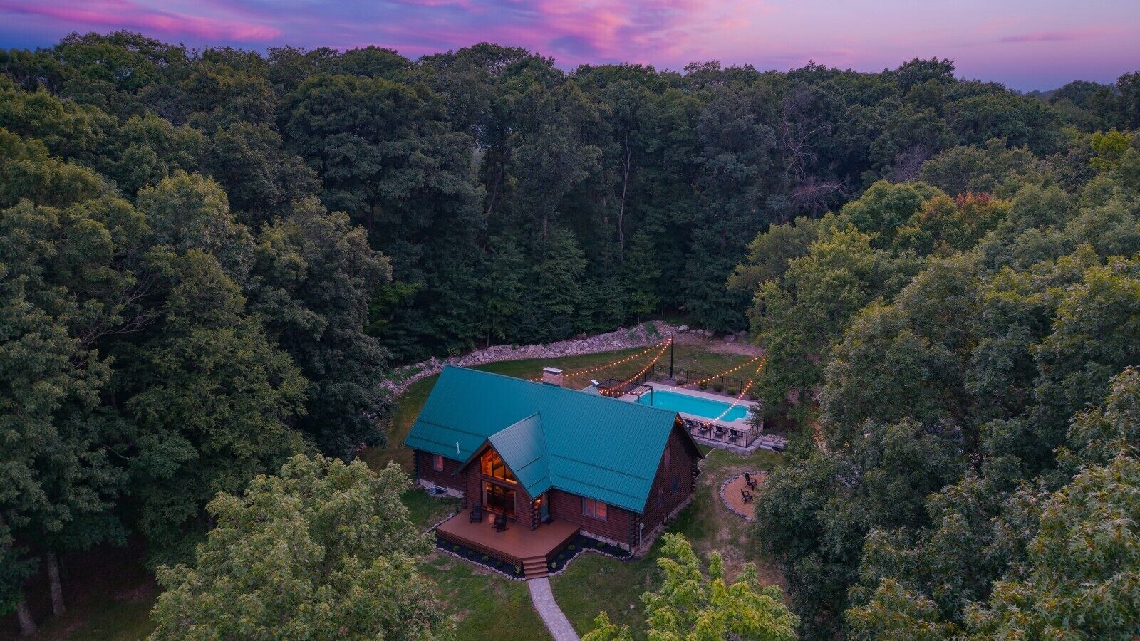 A cabin with a swimming pool surrounded by dense forest.