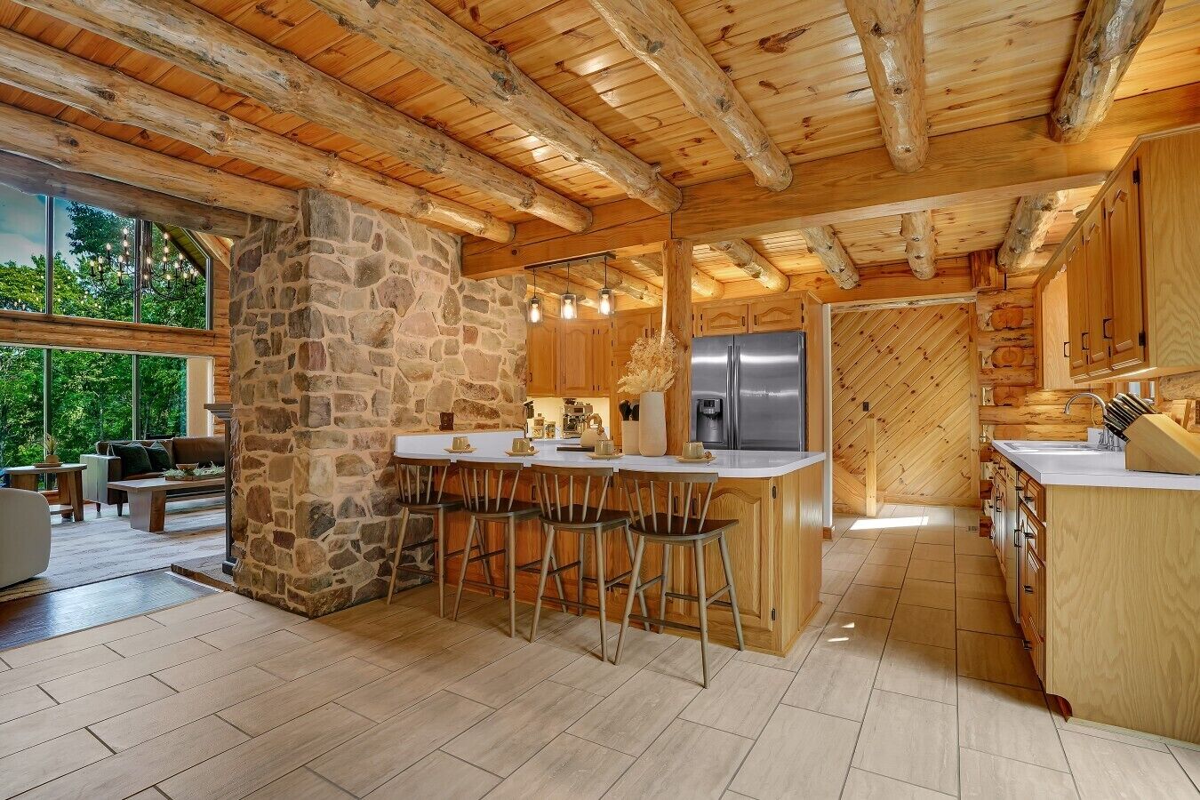 A rustic kitchen with a stone column, wooden beams, and a large island with bar stools.