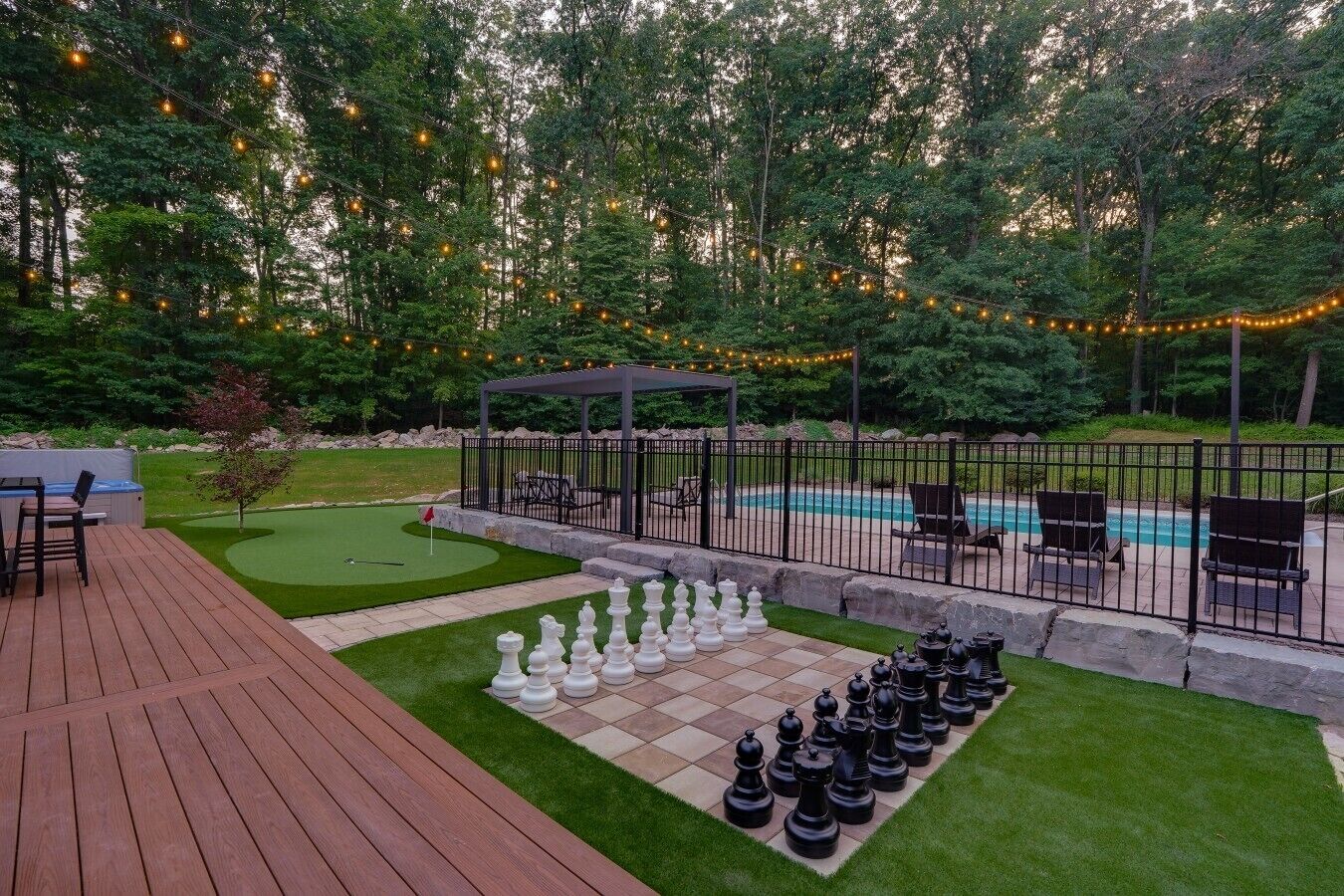 Un patio trasero con piscina, mesa de ajedrez y un pabellón.