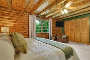 A log cabin bedroom with a bed, a chair, a window, and a wardrobe.