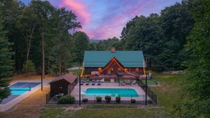 A lodge with a swimming pool, outdoor seating, and a fenced deck area.