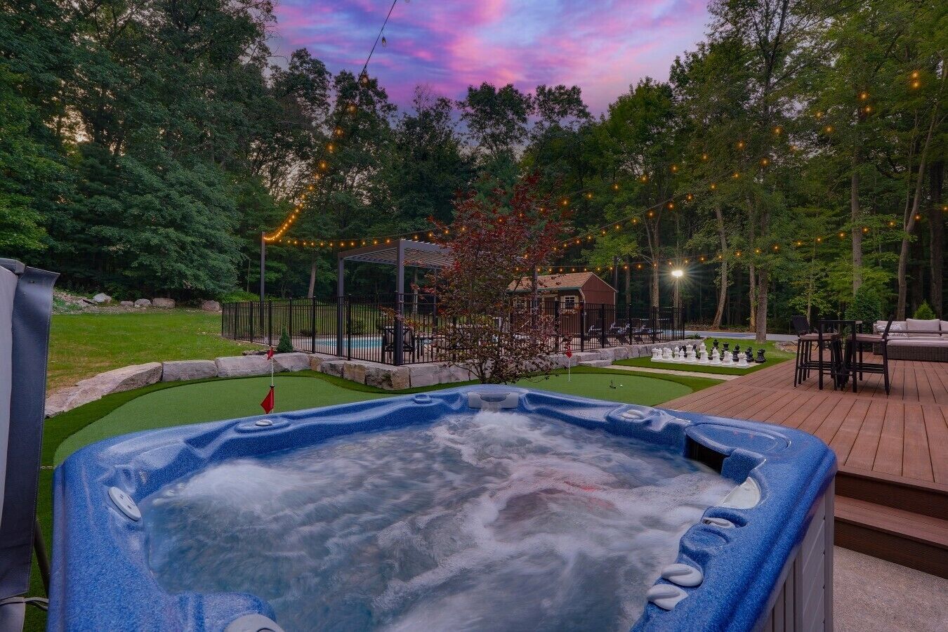 Una vasca idromassaggio circondata da un solarium, una piscina e un gazebo.