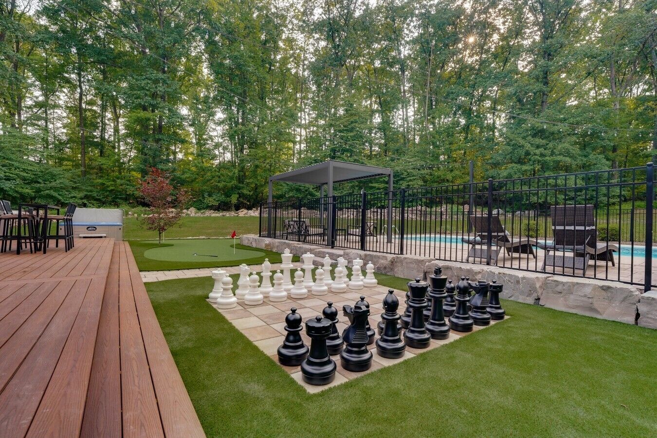 Une terrasse avec un jeu d’échecs installé, une piscine et un espace salon abrité.