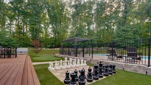 A deck with a chessboard set up, a pool, and a covered seating area. - Pine Mountain Lodge - Pool - Pickleball (Fayetteville)