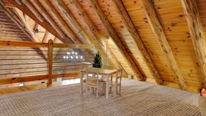 A wooden interior with a sloped ceiling, a table with chairs, and a small Christmas tree. - Pine Mountain Lodge - Pool - Pickleball (Fayetteville)