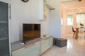 Eine moderne Küche mit Flachbildfernseher, einer kleinen Schranke und einer Essecke mit Tisch und Stühlen.
