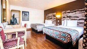Une chambre d’hôtel avec deux lits, un bureau avec une chaise, un miroir et une lampe fixée au mur.