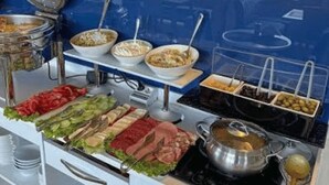 A buffet setup with various food items and a hot pot on a stove. - orbi city (Batumi)
