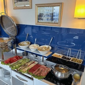 En buffé med olika sorters mat och en gryta som hålls varm på en spis.