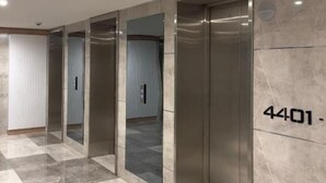 A hallway with a checkered floor, elevators, and a wall with a number sign. - orbi city (Batumi)