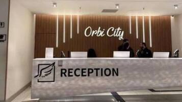 Un mostrador de recepción con un letrero que dice 'Orbi City' y un logotipo que indica zona de recepción.