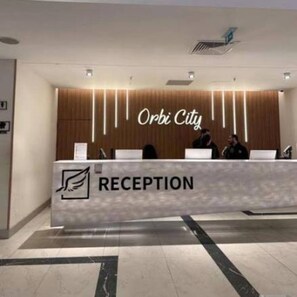 A reception desk with a sign that reads 'Orbi City' and a logo indicating a reception area. - orbi city (Batumi)