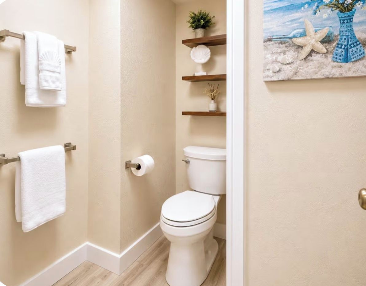 Ein Badezimmer mit Toilette, Handtuchhalter und Ablagefläche mit Dekoration.