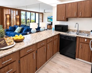 A modern kitchen with wooden cabinets, a black microwave, and a stainless steel sink. - Papakea | 3 Ocean View Villas, Sleeps 12 | Car Incl. w/ 6+ Nights | ML-4262 by KBM (Lahaina)