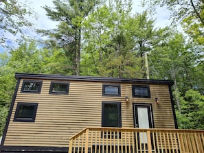 A two-story cabin with a wooden exterior, multiple windows, and a deck.