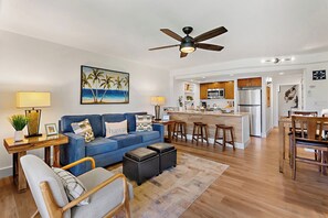 A modern living room with a blue sofa, wooden coffee table, and a ceiling fan. - Papakea | 2 Ocean View Villas, Sleeps 8 | Car Incl. w/ 6+ Nights | ML-4265 by KBM (Lahaina)