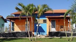 A two-story building with a red-tiled roof and a blue facade, surrounded by palm trees.