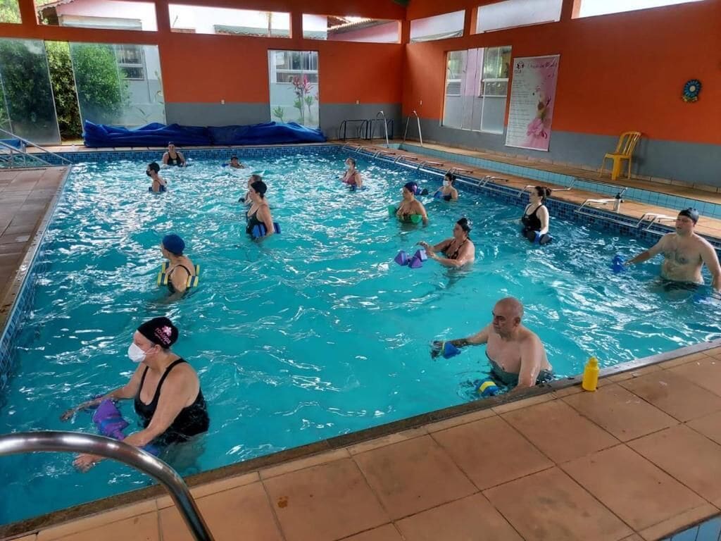Uma piscina com várias pistas de natação, uma cadeira de salva-vidas e uma cadeira amarela à beira da piscina.