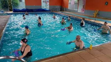 Uma piscina com várias pistas de natação, uma cadeira de salva-vidas e uma cadeira amarela à beira da piscina.