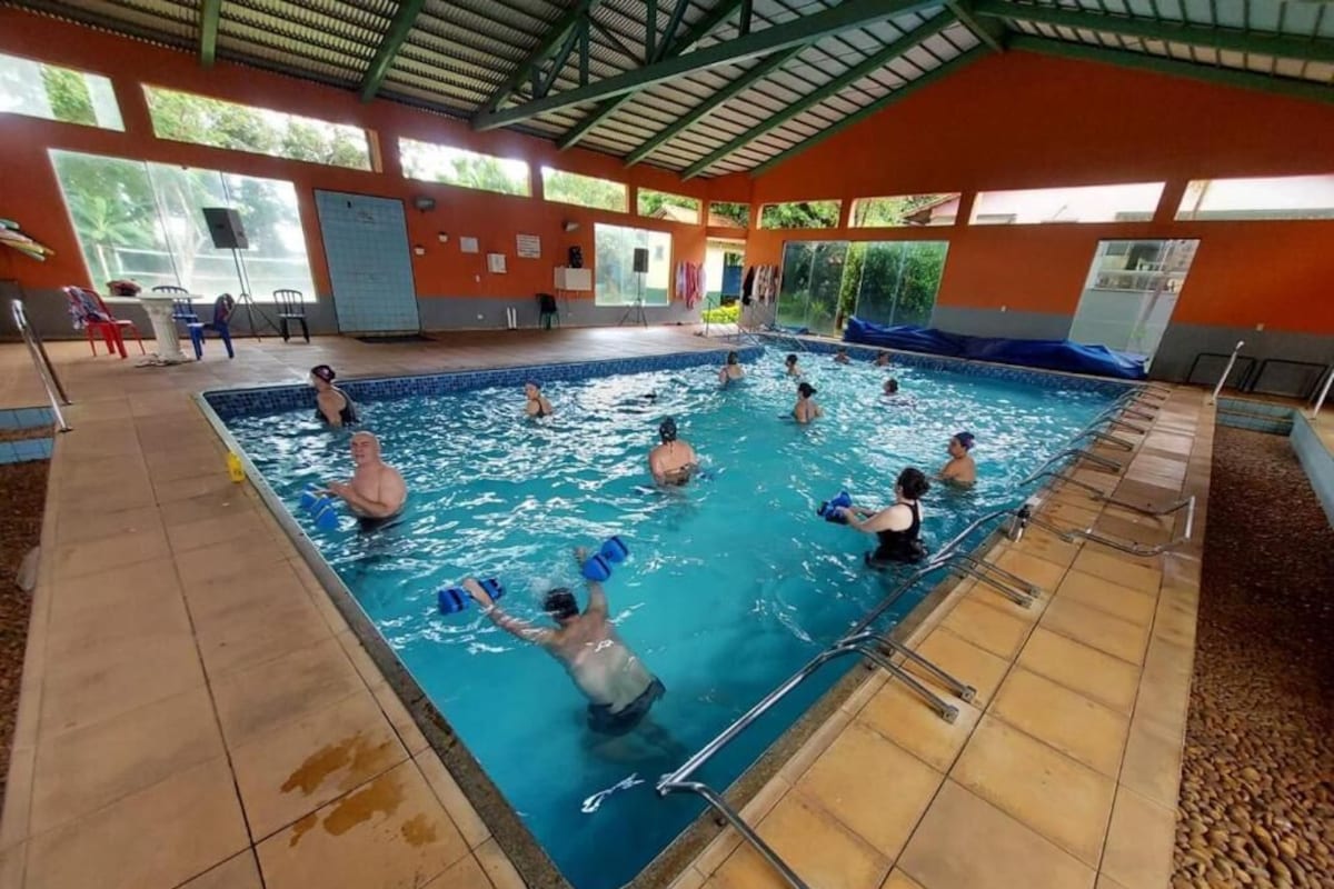 An indoor swimming pool with multiple lanes, a tiled floor, and a covered roof structure.